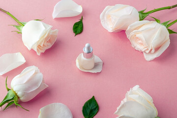 Natural organic homemade cosmetics concept. Skin care (therapy), beauty products: containers with face serum among delicate rose flowers petals on a pink background. Copy space for text, mock up