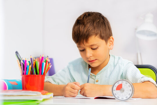 Little boy doing writing exercise with lesson timer