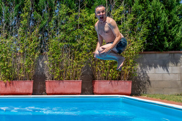 White man with a funny expression takes a bomb dive in a swimming pool on a sunny day