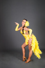 beautiful brunette model in frank yellow suit dances on hight heels in studio