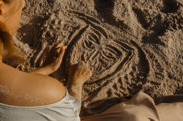 Drawing of a human face in the sand. Summer, vacation