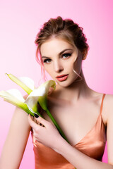 elegant beautiful blonde woman holding calla flowers isolated on pink