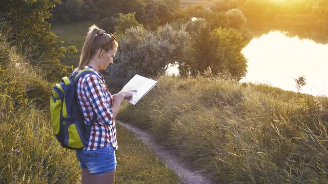 caucasian woman tourist with a map and a backpack on a hike navigates the terrain. Leisure activity