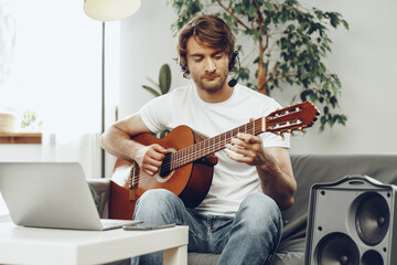 Young man watching guitar tutorial on his laptop