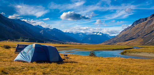 A tent pitched beside a river, surrounded by mountains, in New Zealand
