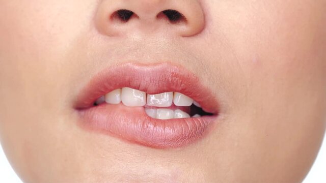 Cropped portrait of woman over white background extreme closeup. Closeup woman biting her lower lip - video in slow motion