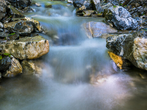 Water stream flowing between rocks into the forest. Water spring in Bucegi National Park.