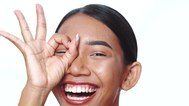 Closeup face of beautiful Asian woman looking at the camera doing doing circle, binocular with hand over white background