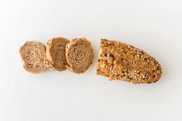 Wholegrain sliced freshly baked bread with flax and sesame seeds on white background. Top view