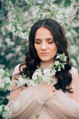 portrait of a beautiful young girl in a light dress on the background of a blooming garden.