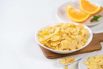 Corn flakes bowl sweeties with milk and orange on white background, close up, fresh and healthy breakfast design concept.