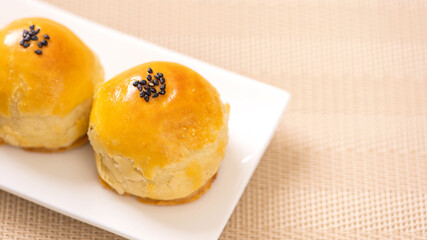 Tasty baked egg yolk pastry moon cake for Mid-Autumn Festival on bright wooden table background. Chinese festive food concept, close up, copy space.