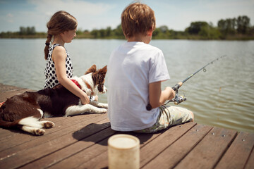 Brother and sister enjoying fishing with their dog