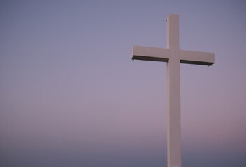 Metal religious cross over a hilltop during a sunset. Copy space