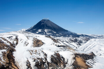 View of the correct cone of the Karymsky volcano in the spring after a snowfall.