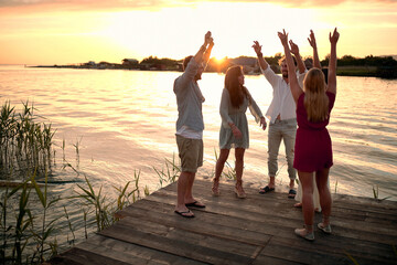 Friends having party at the dock on river at evening.