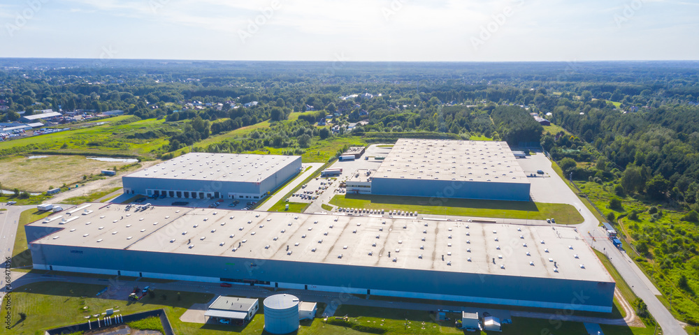 Wall mural Aerial view of warehouse storages or industrial factory or logistics center from above. Aerial view of industrial buildings and equipment at sunset, toned