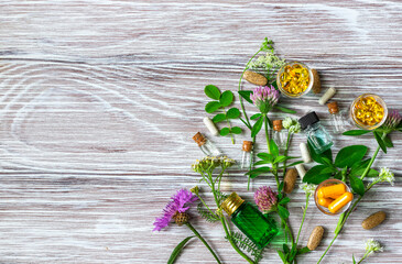 Medical flowers herbs essential oils in bottles for natural diseases treatment on wooden table. Concept of natural cosmetics.