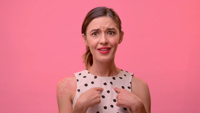Young woman standing on a background of a pink background. She is desperate to be accused of what she did not do. The woman does not succumb to provocation and defends her opinion.