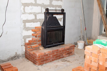 black cast iron firebox with a lift door stands on the brickwork in the living room