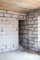 interior of bedroom under construction with niche for wardrobe behind bed in cottage built of foam blocks