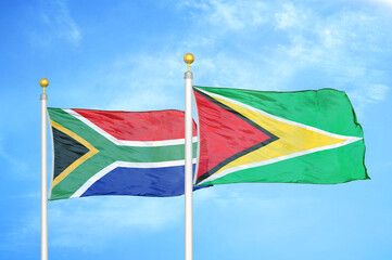 South Africa and Guyana two flags on flagpoles and blue sky
