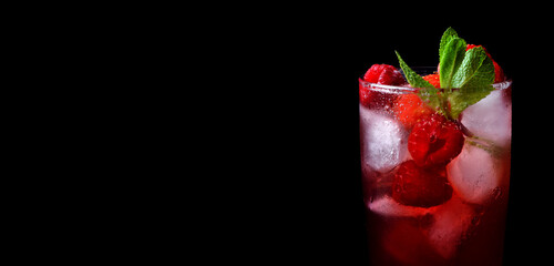 Red drink with ice, raspberries and mint in a glass against the black background. Copy space