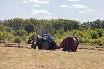 tractor in field throwing out hay roll