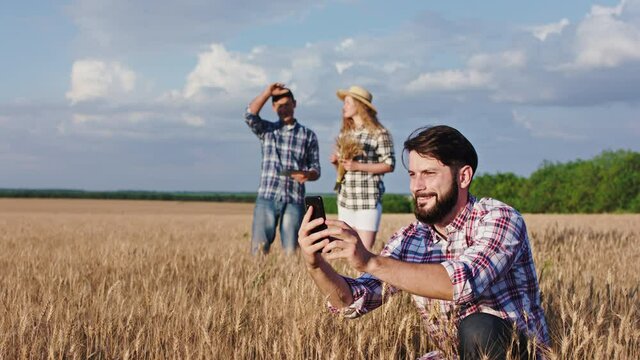 In a large wheat field concept of family business in a agriculture old man farmer and family happy examinations the wheat and they feels very happy a guy take some pictures of the phone. Shot on ARRI