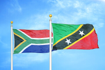 South Africa and Saint Kitts and Nevis two flags on flagpoles and blue sky