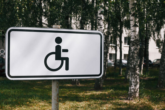 Disabled parking lot sign with residential building and birch trees on background