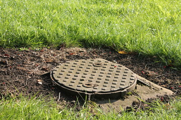Round metal manhole cover surrounded by grass - 368481110