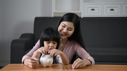 Family concept. Mother is teaching her daughter to save by dropping a piggy bank. 4k Resolution.