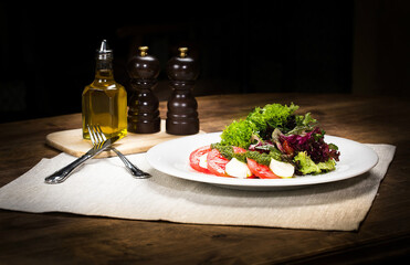 on a wooden table is a plate of salad, next to oil and seasonings