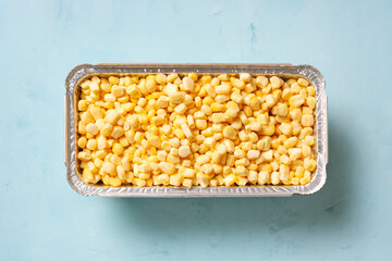 Frozen corn on a blue surface, flat lay, horizontal orientation.