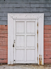 Old closed wooden white door with colorful wood wall for concept background and texture.