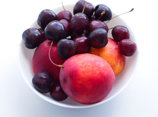 three peaches, nectarine and a handful of cherries are in a white plate. Isolate, a natural dessert made from berries. A tasty, healthy snack, a slice of summer, a harvest. Fruit on white, fruit plate
