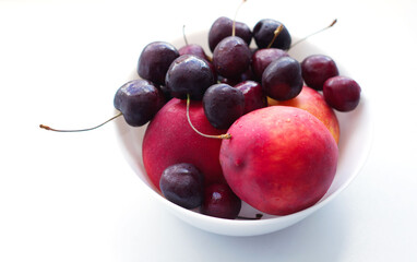 three peaches, nectarine and a handful of cherries are in a white plate. Isolate, a natural dessert made from berries. A tasty, healthy snack, a slice of summer, a harvest. Fruit on white, fruit plate