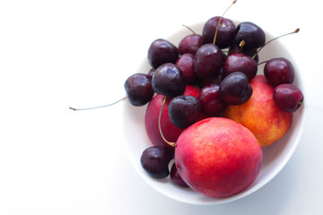 three peaches, nectarine and a handful of cherries are in a white plate. Isolate, a natural dessert made from berries. A tasty, healthy snack, a slice of summer, a harvest. Fruit on white, fruit plate