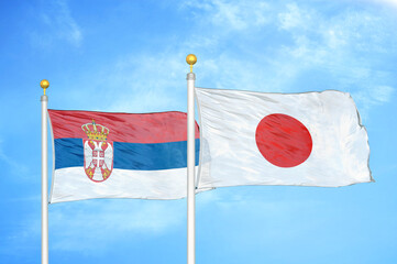 Serbia and Japan two flags on flagpoles and blue sky