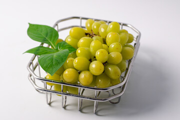 Green grapes in a metal basket on a white background