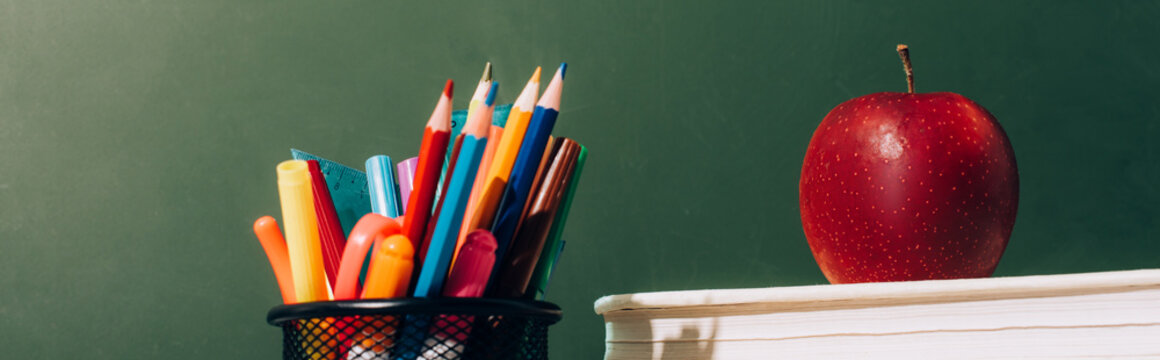 Website Header Of Pen Holder With Color Pencils And Pens, And Ripe Apple On Books Near Green Chalkboard