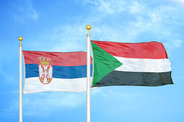 Serbia and Sudan two flags on flagpoles and blue sky