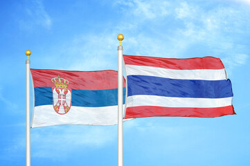 Serbia and Thailand two flags on flagpoles and blue sky