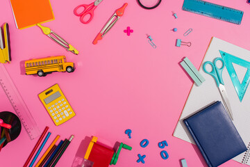 top view of school supplies and school bus model on pink with copy space