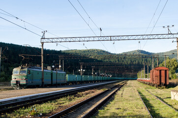 Obraz premium Railway tracks and wagons of the station against the background of the high Carpathian mountains