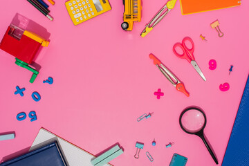 top view of school stationery and school bus model on pink with copy space