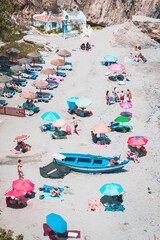 Beach with people with umbrellas, towels and sunbathing