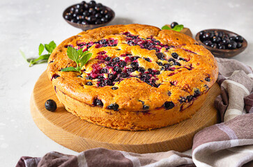 Sweet homemade cake or with cornmeal and black currant decorated with mint, selective focus. Light grey background. Summer baking.