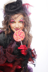 Girl with with creative make-up holds lollipop.